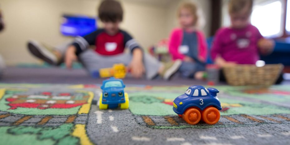 Spielautos auf der Teppichstraße vor spielenden Kindern